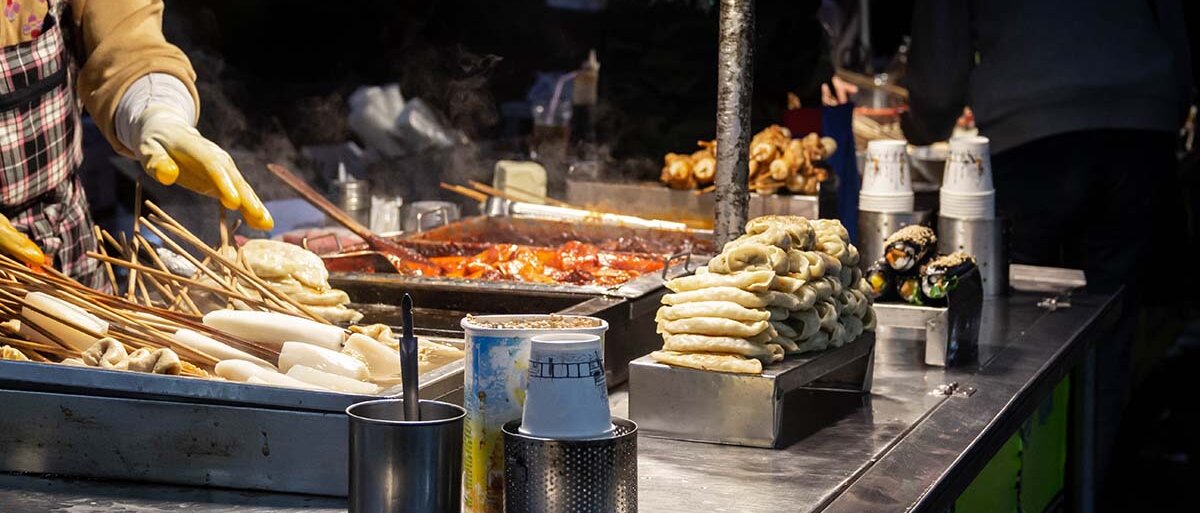 Ein Streetfood-Stand auf dem koreanischen Nachtmarkt mit Tteokbokki, Fischkuchen und Gimbap.