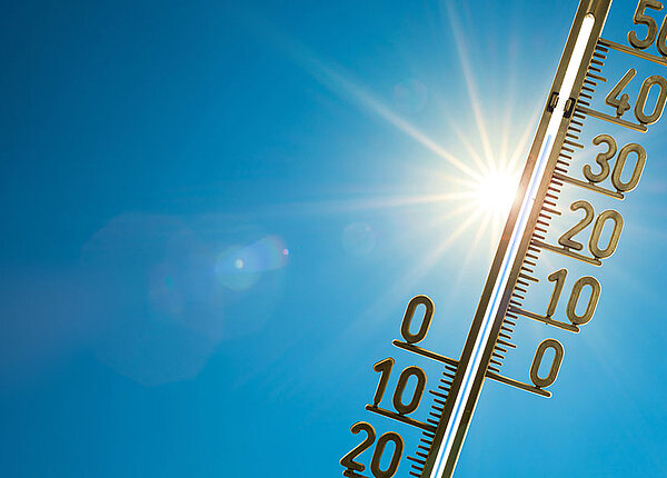 Thermometer mit strahlender Sonne und blauem Himmel