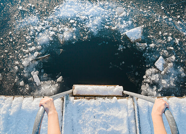 Ein Loch in einem zugefrorenen Gewässer, in das jemand reinspringen möchte