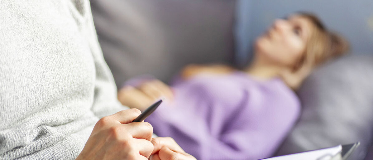 Frau liegt auf dem Sofa und spricht mit Psychotherapeutin