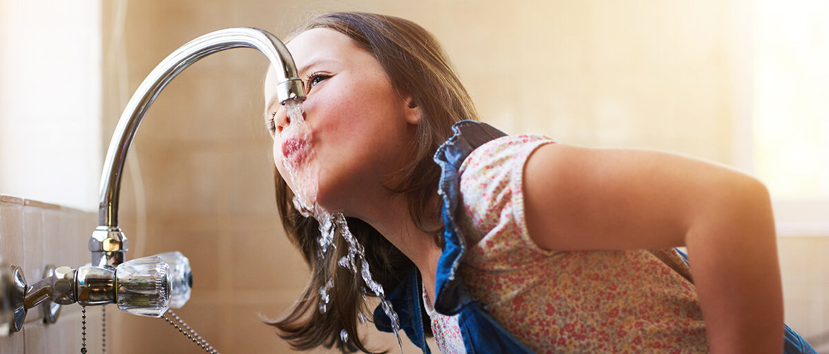 Ein Kind trinkt aus einem Wasserhahn