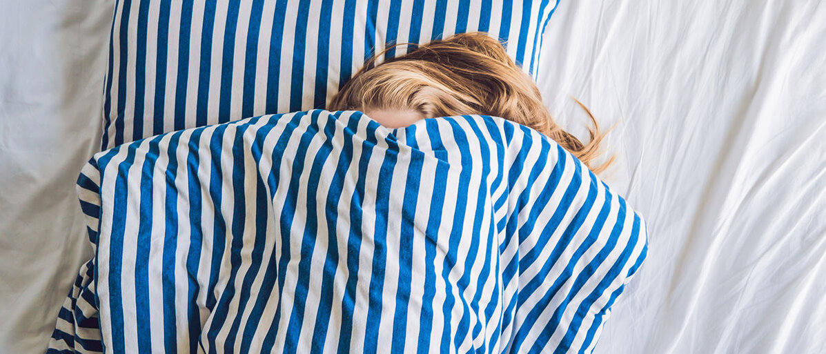 Schlafstörungen Frau, die sich unter der Bettdecke versteckt