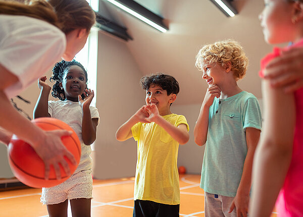 Mädchen und Jungen mit Lehrerin in Sporthalle