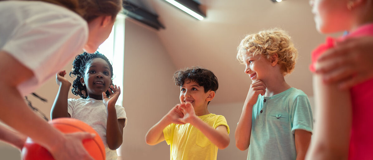 Zusammenhang Bewegung und psychische Gesundheit bei Kindern Mädchen und Jungen mit Lehrerin in Sporthalle