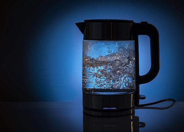 Umweltfreundlich und nachhaltig Kaffeemaschine und Wasserkocher entkalken In einem Wasserkocher aus Glas blubbert das Wasser.