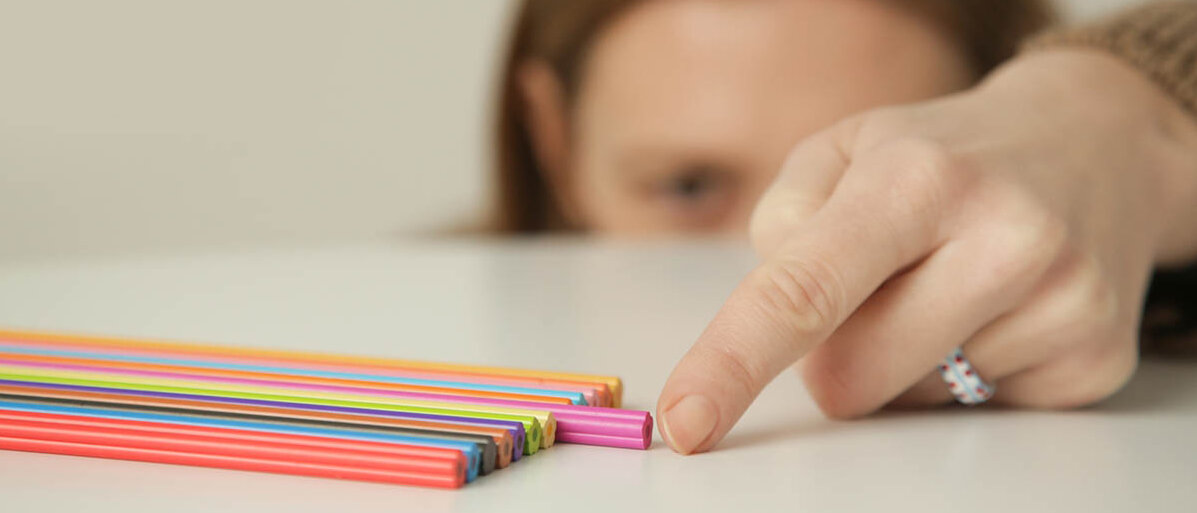 Eine Frau hat Stifte sortiert und verschiebt gerade den letzten so, dass er exakt auf einer Höhe mit den anderen liegt.