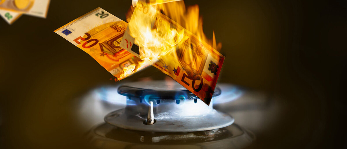 Eine Gasflamme verbrennt Geldscheine
