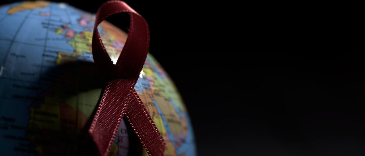 Weltkugel und die Aids Schleife auf schwarzem Hintergrund