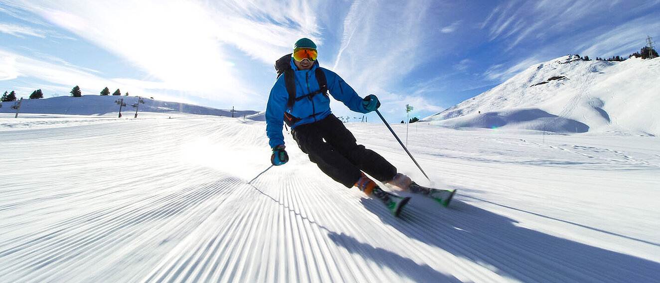 Tipps fĂĽr gesunden Wintersport Skifahrer auf der Piste bei gutem Wetter