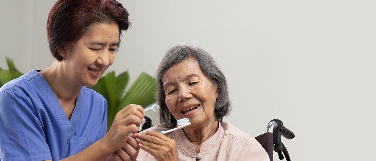 Eine Pflegekraft hilft einem älteren Menschen beim Zähneputzen