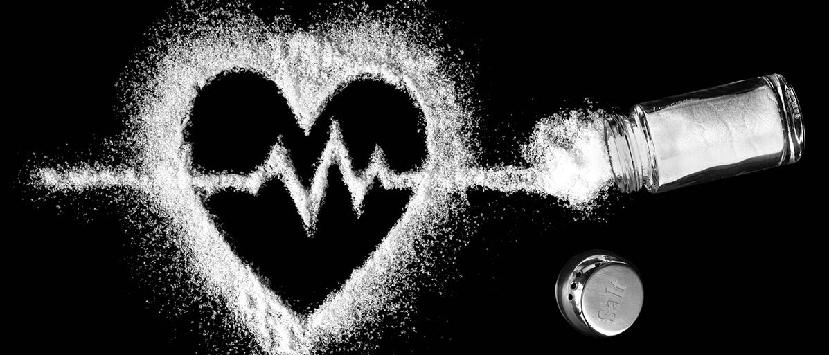 Herz aus Salz und mittendurch eine EKG-Linie auf schwarzem Hintergrund