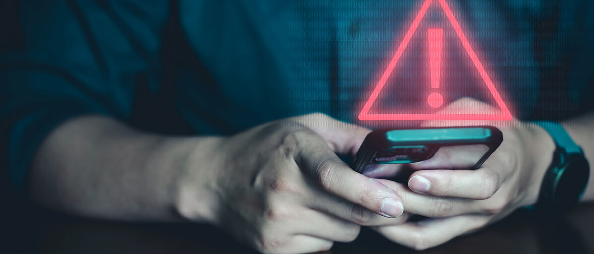Giftnotruf statt KI Mann hĂ€lt Handy in der Hand. DarĂŒber rotes Warnzeichen.