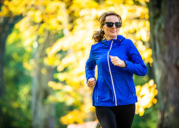 So können Frauen gezielt ihre Herzgesundheit verbessern Frau mittleren Alters mit Sonnenbrille läuft im Park