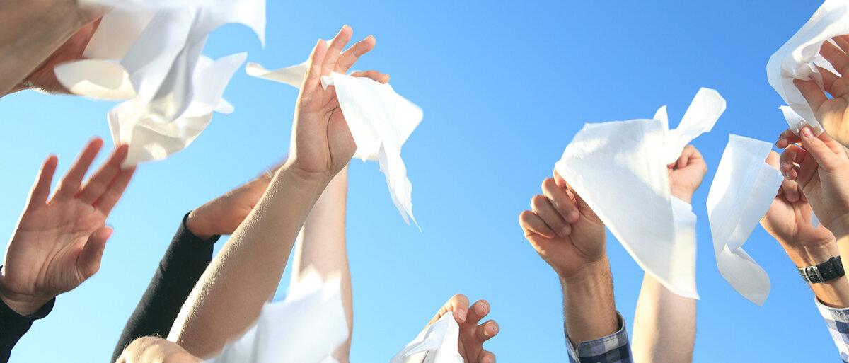 Winkende Hände mit Taschentüchern vor blauem Himmel