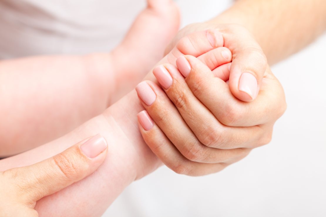 Ein Babyfuß wird von einer Frauenhand massiert.