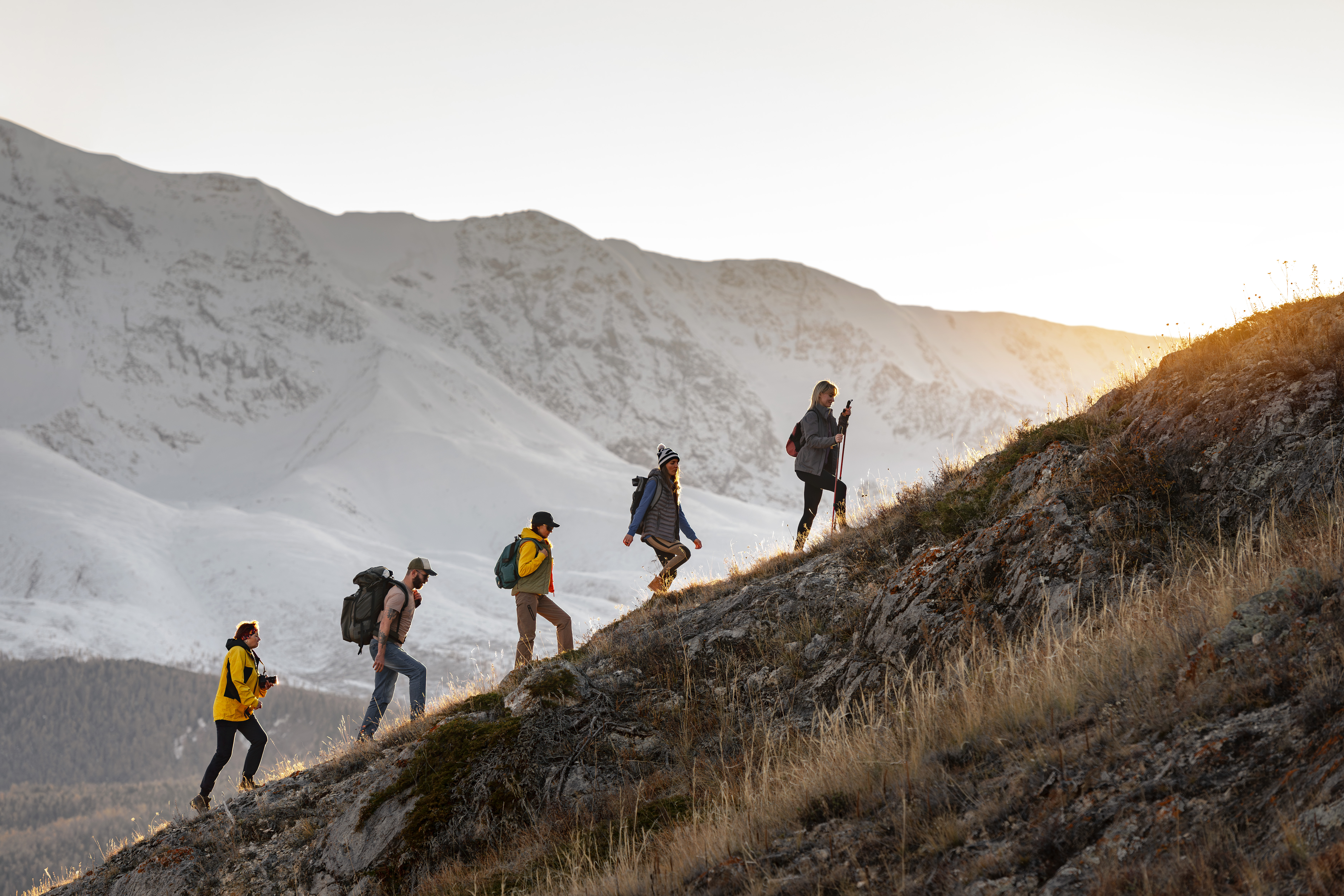 5 Personen in Trecking-Kleidung steigen hintereinander einen steilen Berg hinauf. 