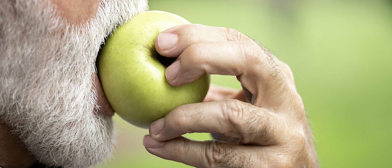 Mann beißt in Apfel.