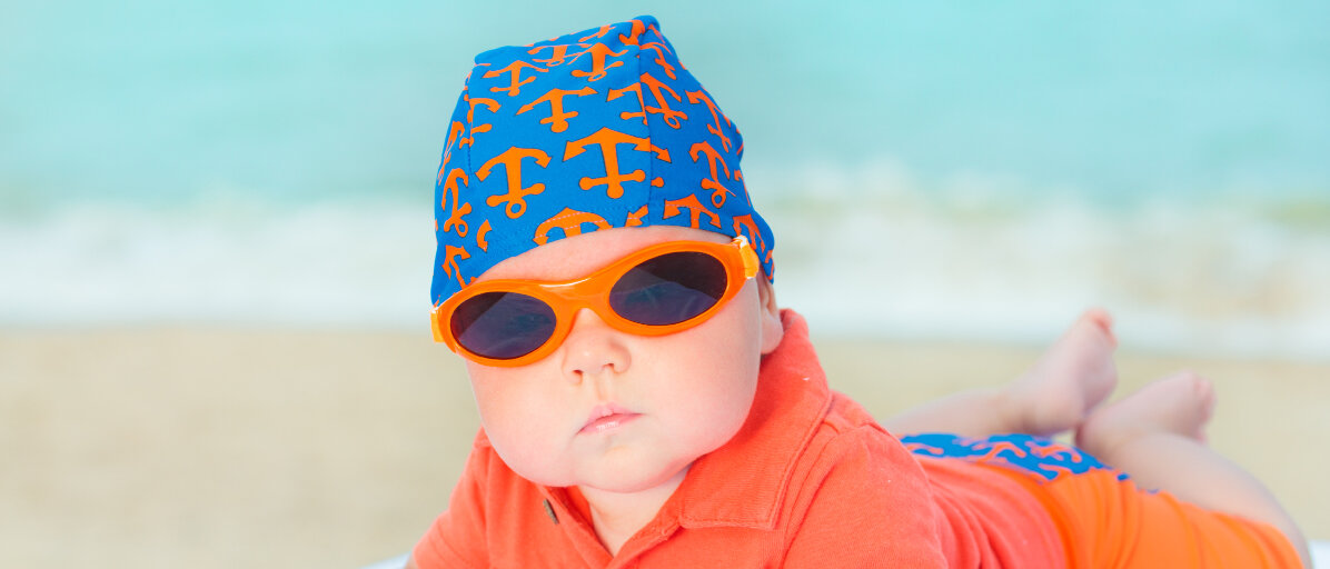 Baby mit Sonnenbrille am Strand.