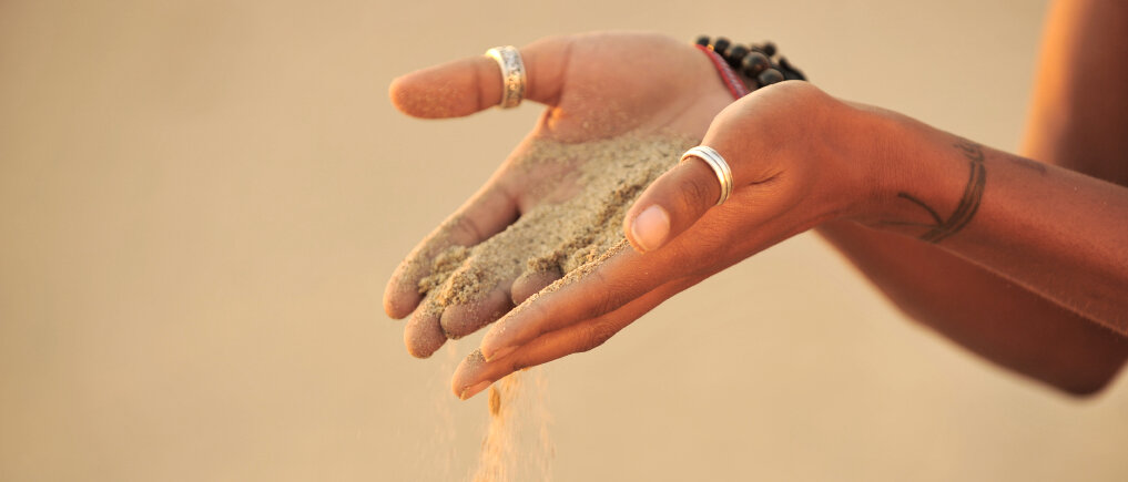 Sand rieselt aus der Hand.