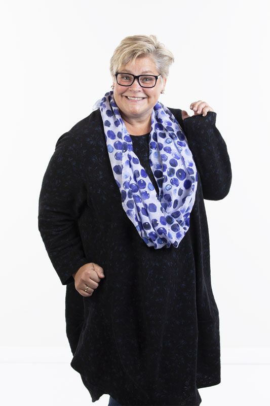 Yvonne Schilling lächelt in die Kamera. Sie trägt eine dunkle Tunika und einen blau-getupften Loop-Schal.