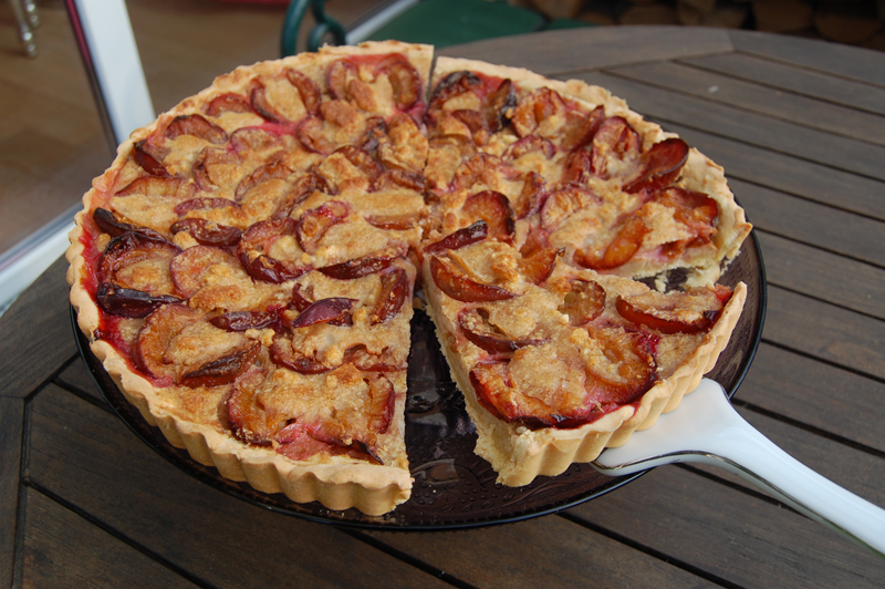 Pflaumentarte Ein Stück von einer Pflaumentarte ist angeschnitten.