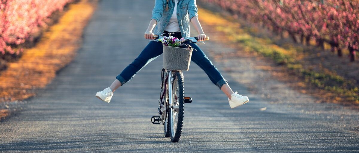 Eine glückliche junge Frau die auf dem Fahrrad einen Berg herunter rollt.