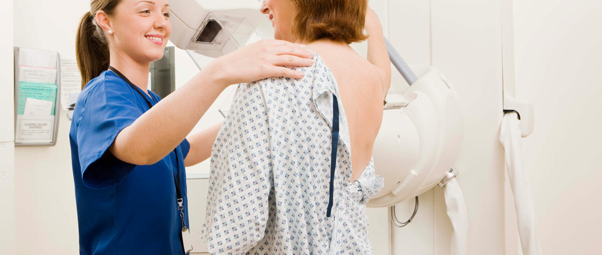 Frau mit Arzthelferin während einer Mammografie, Frau ist von hinten abgebildet