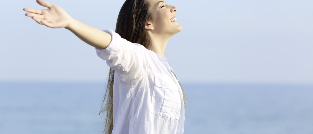 Frau lächelt mit ausgebreiteten Armen. © AntonioGuillem / iStock / Getty Images Plus
