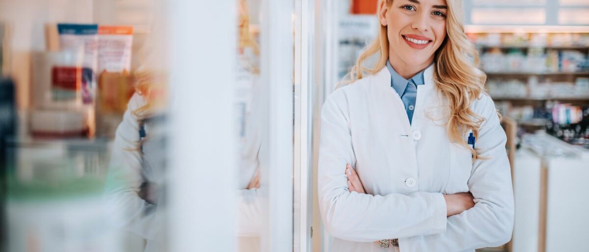 Apotheke Eine Apothekerin lehnt sich gegen einen Schrank mit Medikamenten.