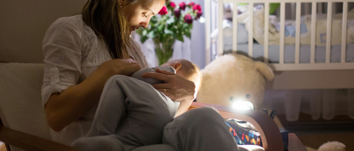 Eine Frau, die nachts ihr Baby im Kinderzimmer stillt