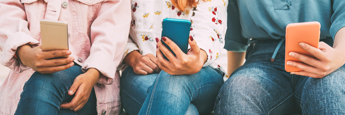 Digitale Angebote Drei Frauen mit Handy in der Hand sitzen auf einer Bank