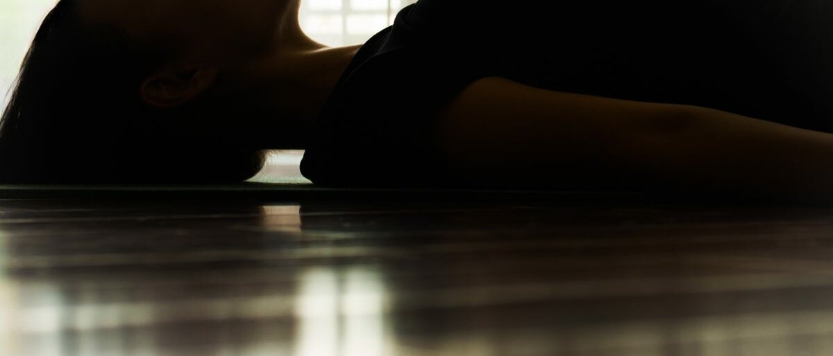 Eine Frau, die auf einer Yoga-Matte liegt und entspannt.