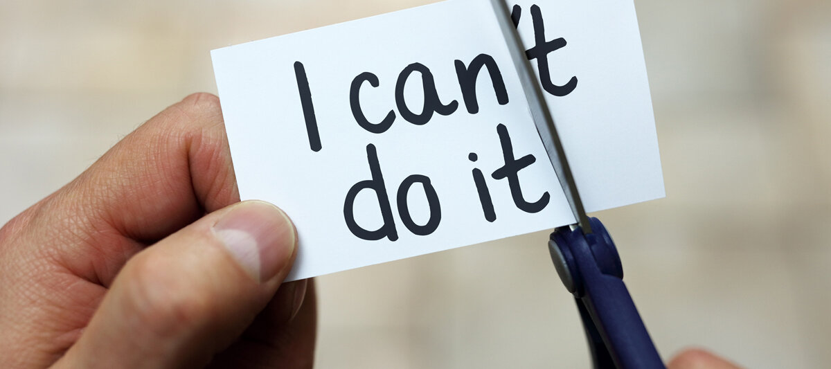 Mit einer Schere wird von einem Zettel ein Stück abgeschnitten, so wird aus der Aufschrift "I can´t do it" "I can do it".