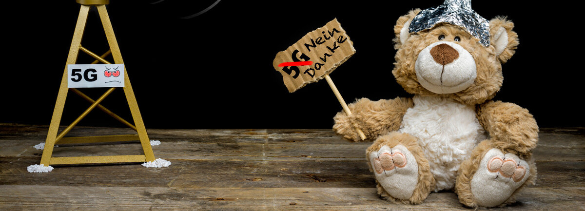 Ein Teddybär mit Aluhut hält ein Schild hoch: 5G, nein Danke.