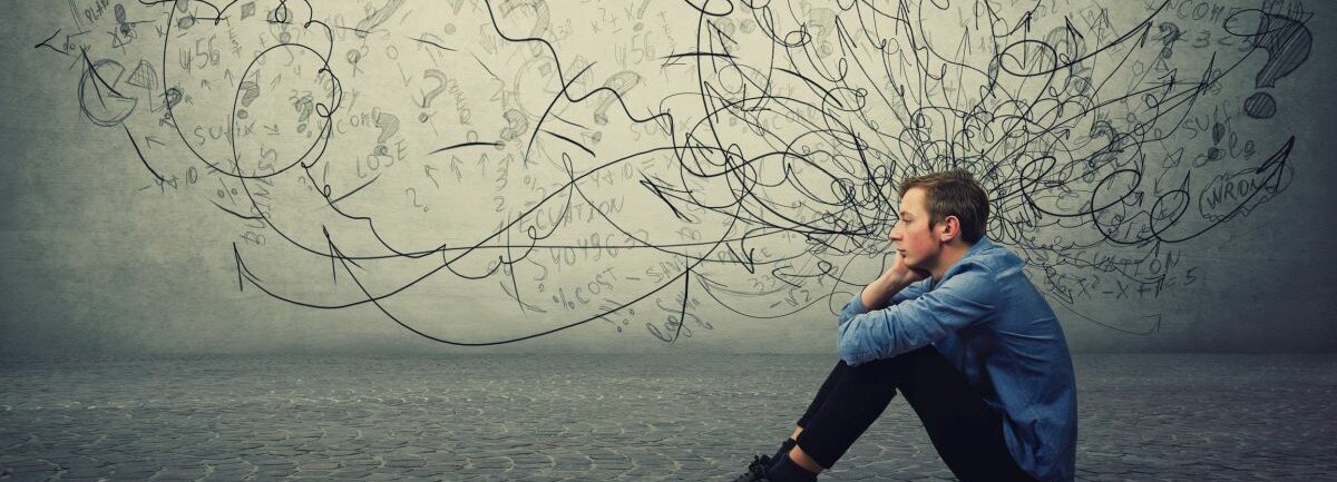 Stress Ein junger Mann sitzt auf Kopfsteinpflaster und fühlt sich gestresst.