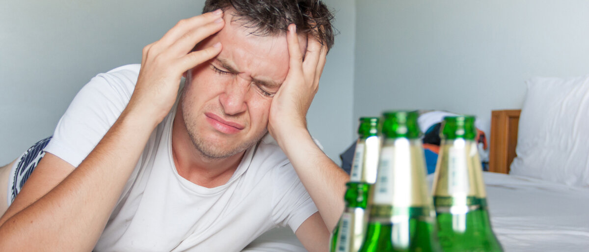 Mann hat Kopfschmerzen nach Alkoholkonsum.