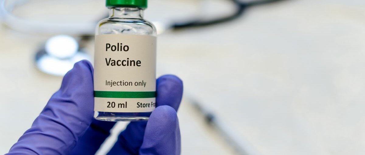 Der Polio-Impfstoff in einer Hand mit blauem Einweghandschuh.