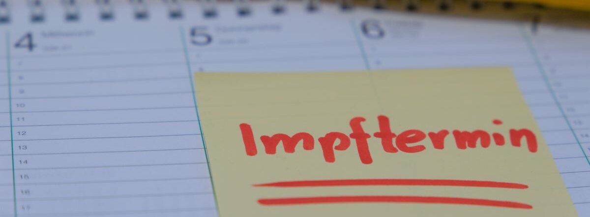 Ein Kalender auf dem ein Post-It klebt. Darauf steht: Impftermin