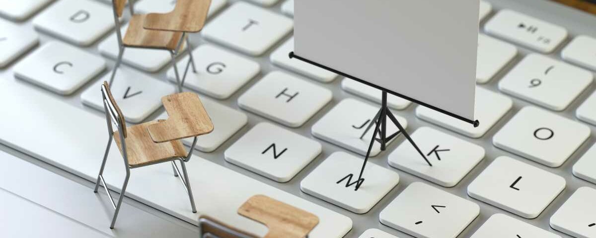 Kleine Figuren einer Stativleinwand und mehrerer Stühle mit Schreibfläche stehen auf einer Laptoptastatur.