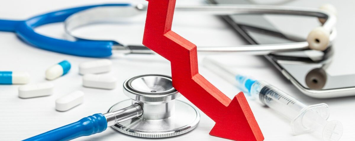 Grafik Im Hintergrund liegen auf weißem Untergrund Utensilien eines Arzts. Im Vordergrund befindet sich ein grafischer Pfeil, der nach unten zeigt.