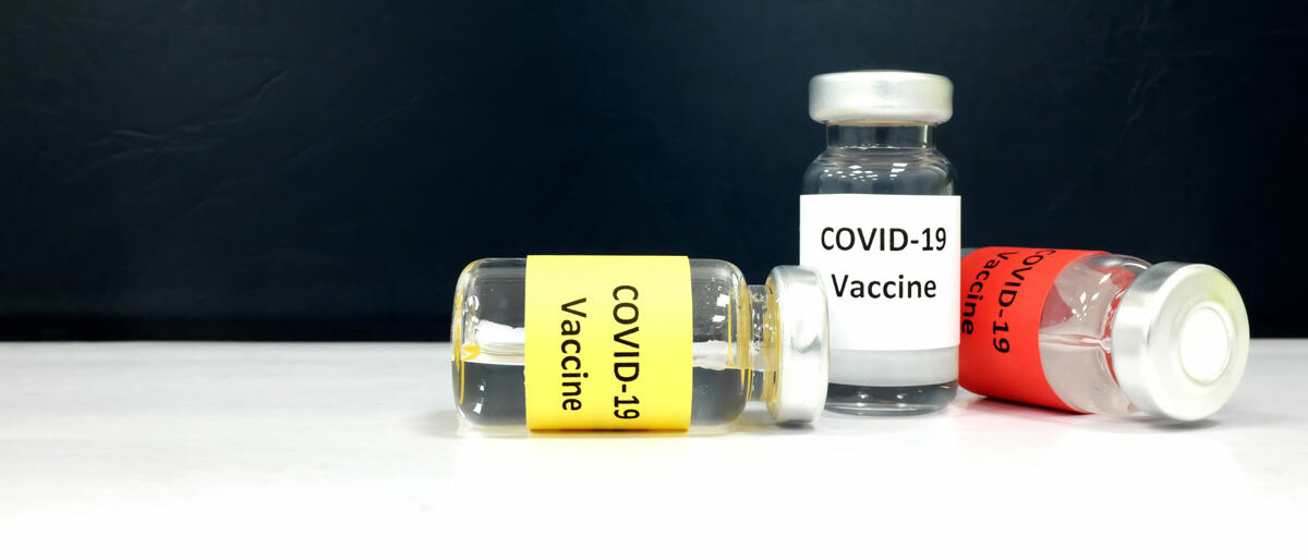 Drei Impfstofffläschchen, alle sind mit "COVID-19" beschriftet, aber in anderen Farben.