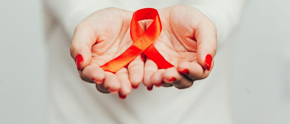 AIDS Eine Frau hält die Aids-Schleife in ihren Händen