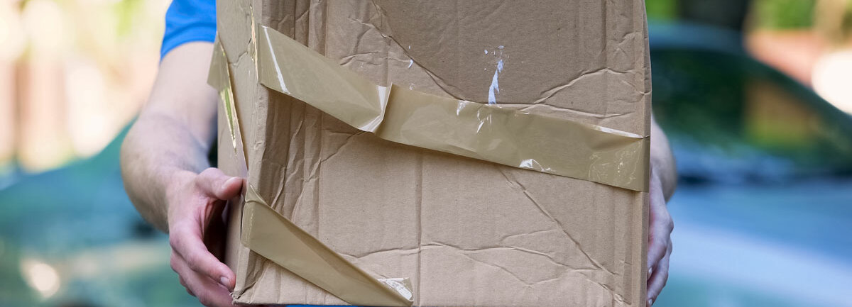 Rx-Versandverbot ein Paketbote hält ein zerbeultes Paket hoch