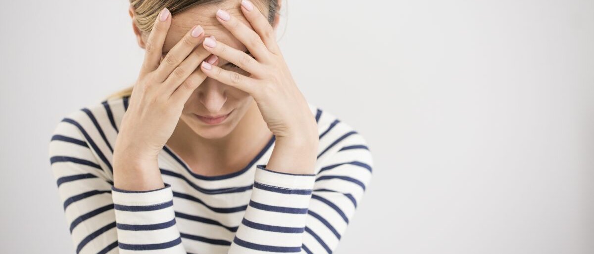 Eine Frau fasst sich an den Kopf.