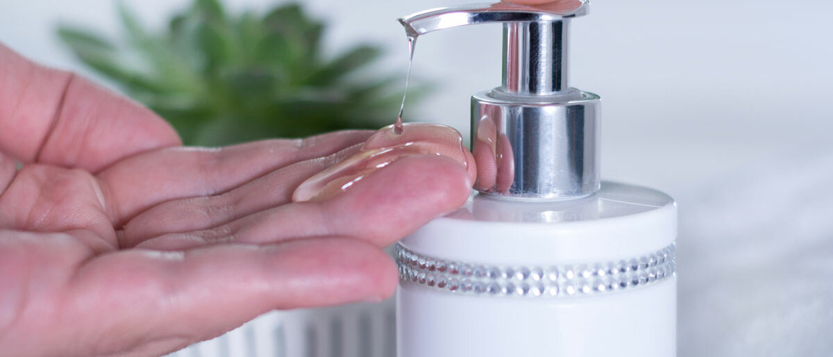 Eine Hand drückt auf einen Flüssig-Gel-Spender