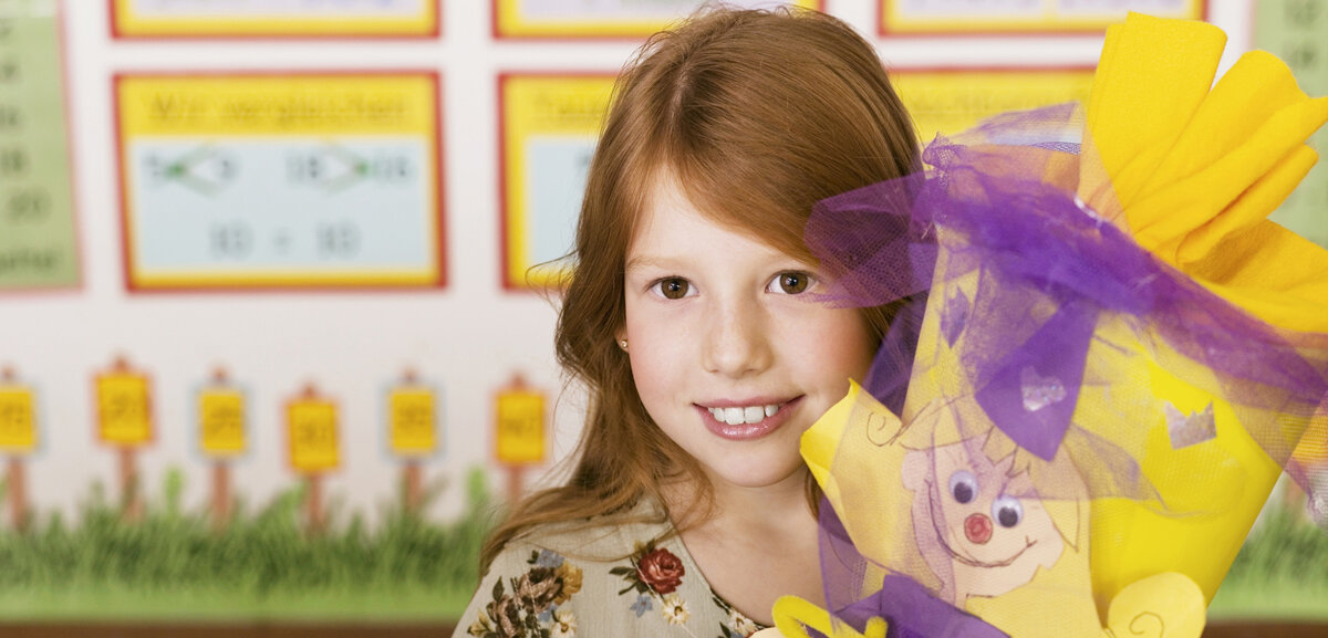 Schultüte Ein Mädchen hält ihre Schultüte und lächelt, sie hat schöne Zähne.