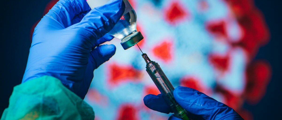 Impfung Jemand mit Einweghandschuhen zieht mit einer Spritze den Impfstoff aus der Flasche.