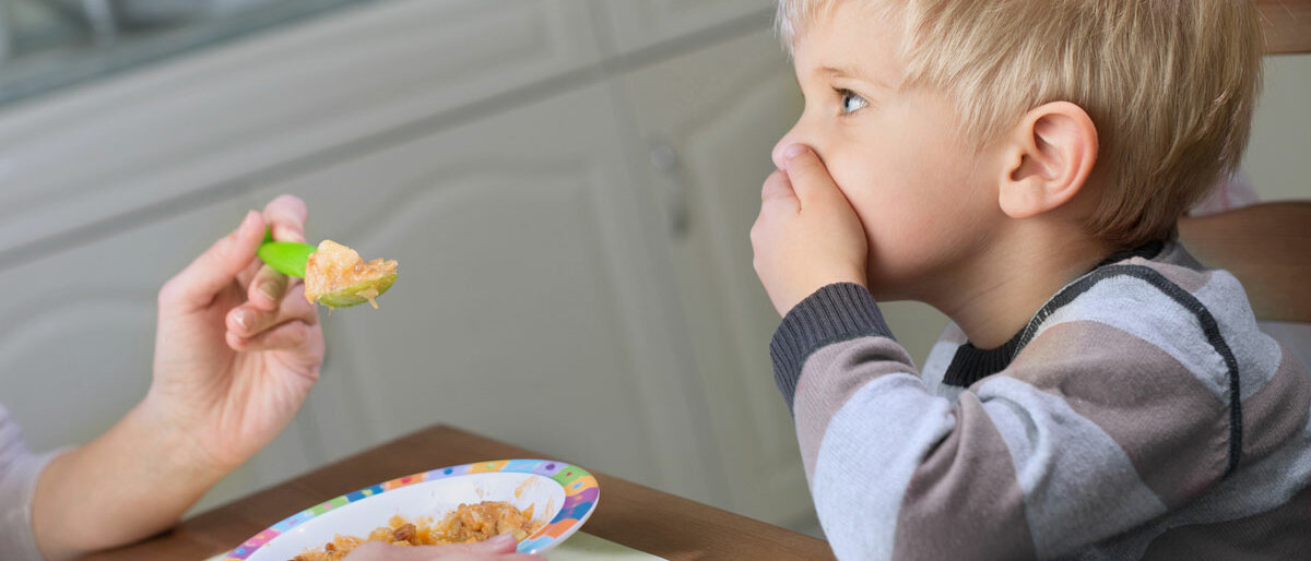 Ein Kind, das das Füttern verweigert, in dem es sich den Mund zu hält.