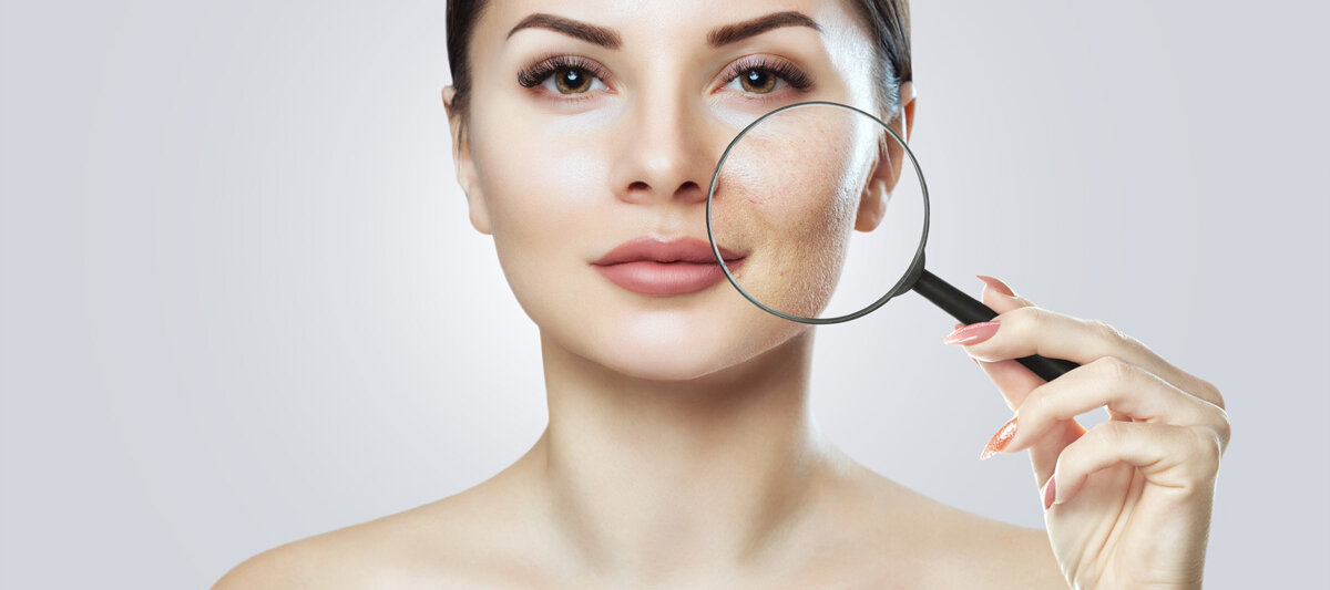 Eine Frau hält sich eine Lupe ins Gesicht