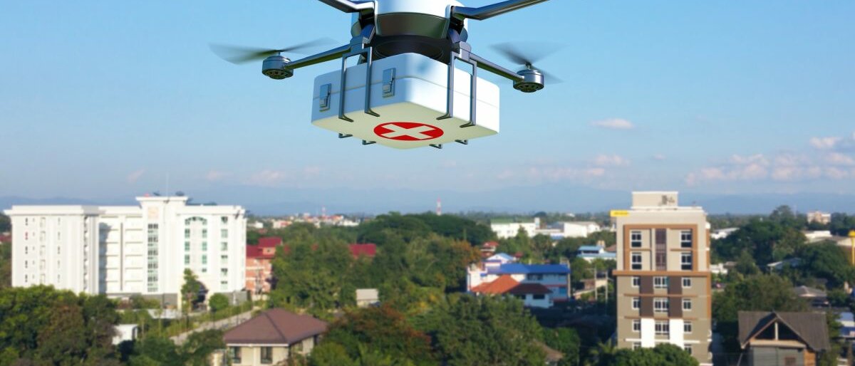 Eine Drohne mit Medizinkasten fliegt über eine Stadt.